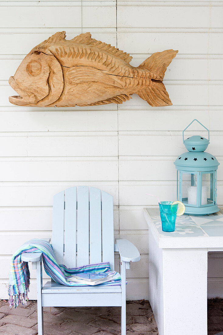 Fisch-Skulptur aus Holz an der Bretterwand über hellblauen Deckchair
