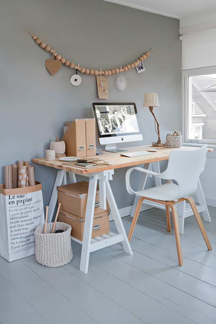 Schreibtisch mit weißer Stuhl, darüber Dekoration aus Holzperlen an grauer Wand im Arbeitszimmer