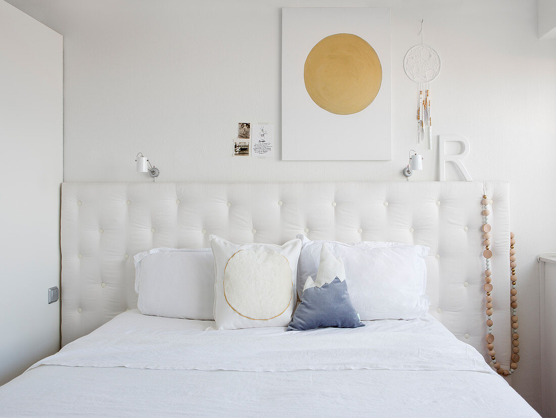 Kissen auf Doppelbett mit Betthaupt, darüber Dekoration an Wand
