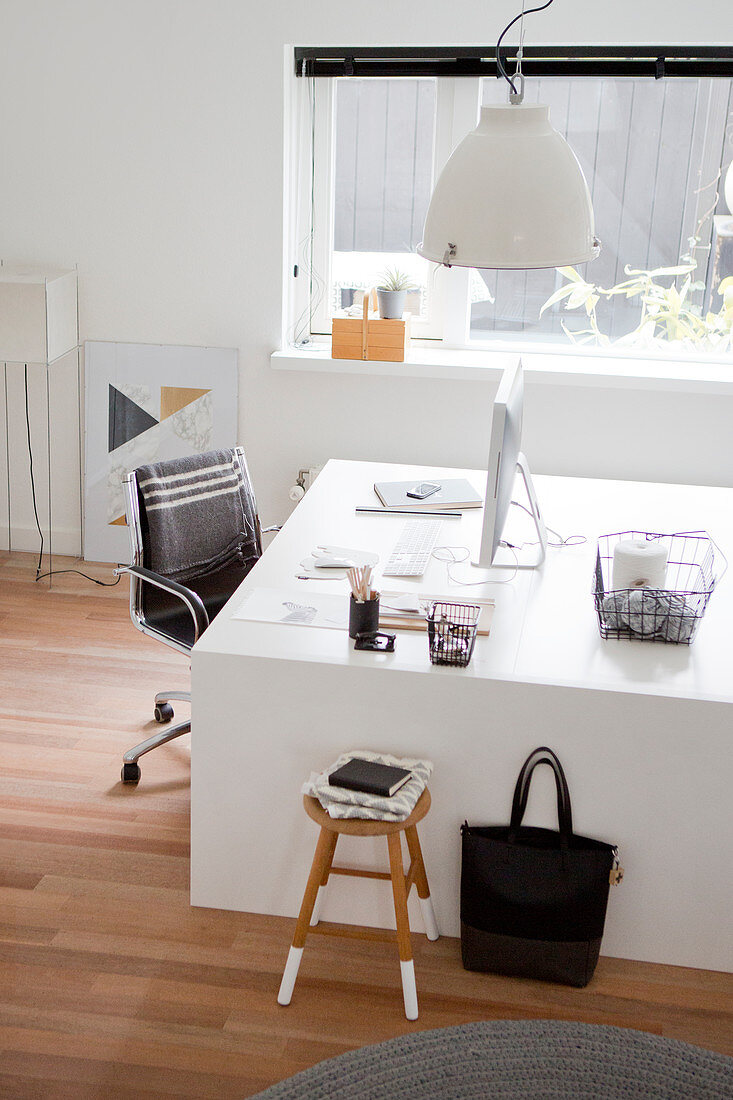 White designer desk and black swivel chair in study