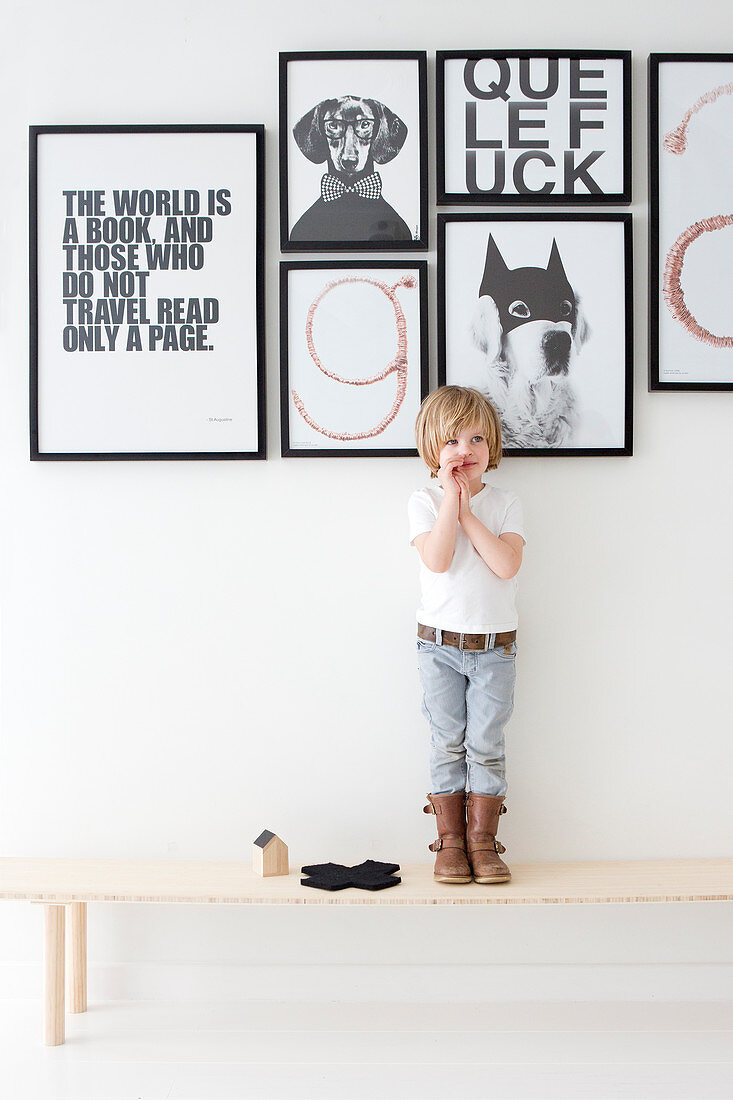Junge steht auf Holzbank vor schwarz-weißen Botschaften an Wand