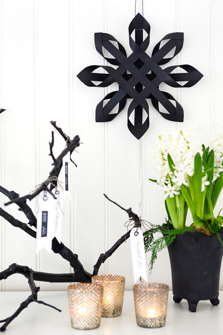 Black paper star on white wall, hyacinth and votive candles lit