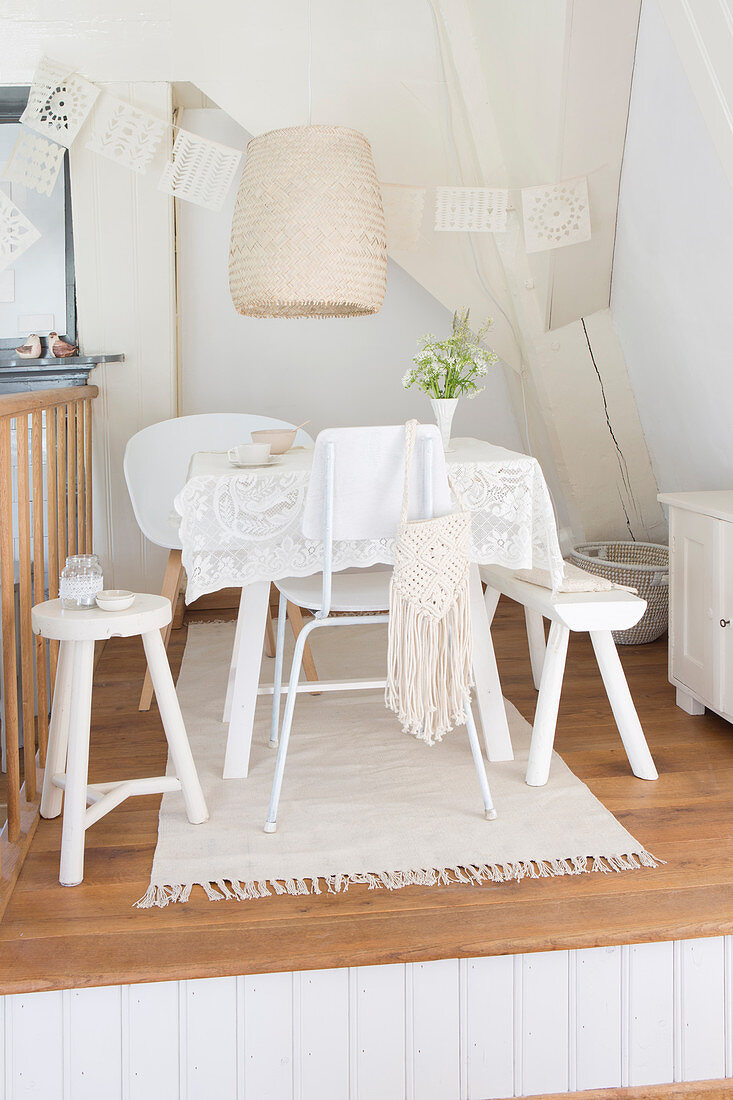 Various chairs and bench around a table with white lace table cloth