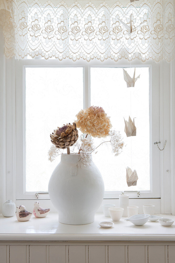 Vase mit getrockneten Blüten auf Fensterbank