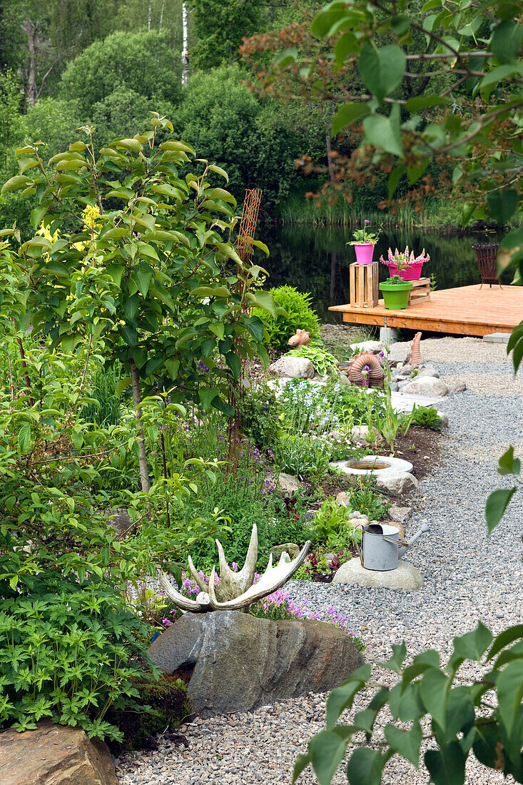 Summertime in a garden with gravel path to pond