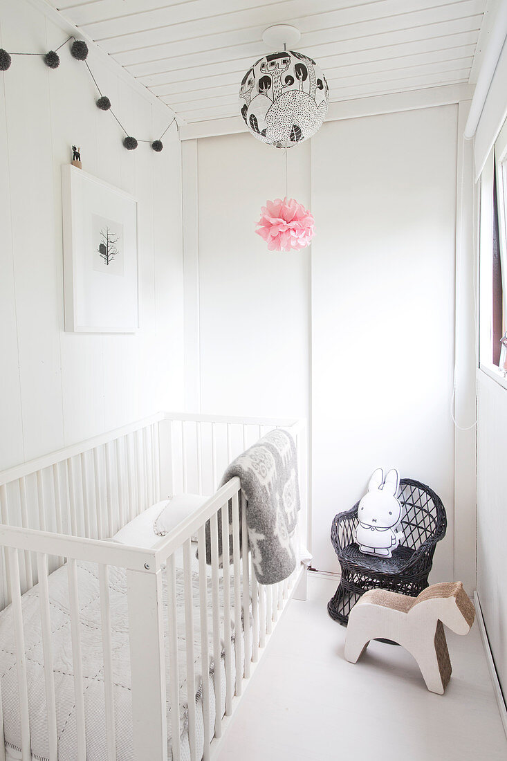 Gitterbett, Holzpferd und Kinderstuhl mit Hasenfigur in weißem Kinderzimmer