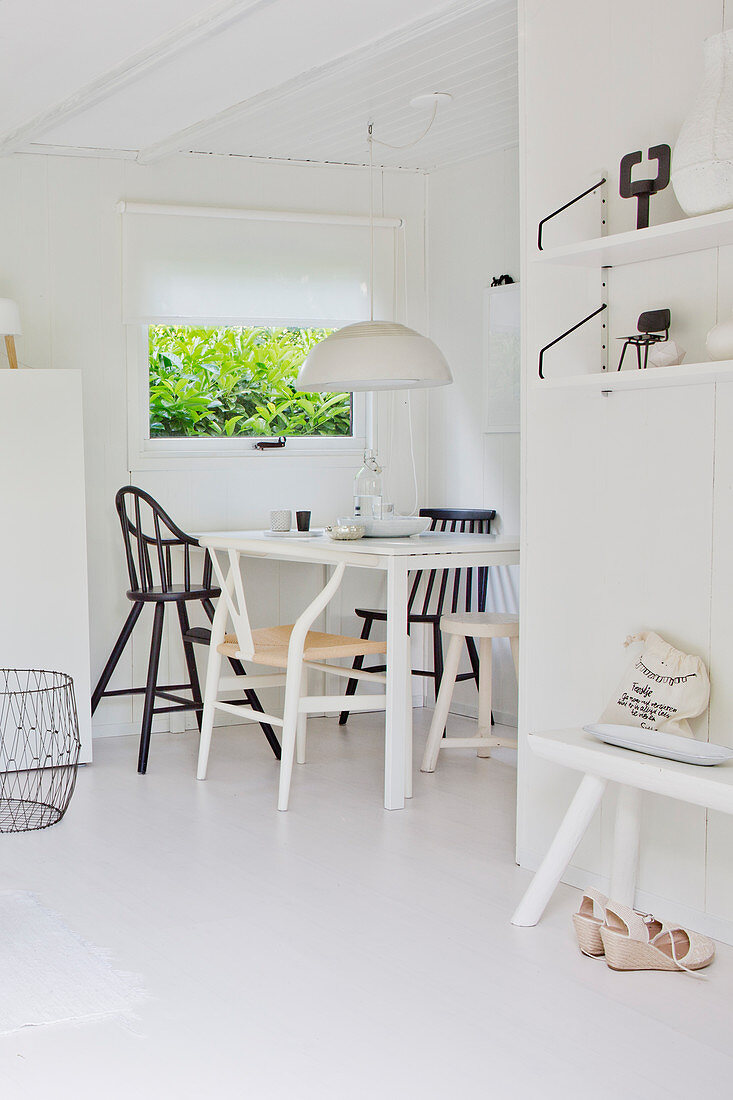 Blick auf Essbereich mit verschiedenen Stühlen in weißer, offener Küche