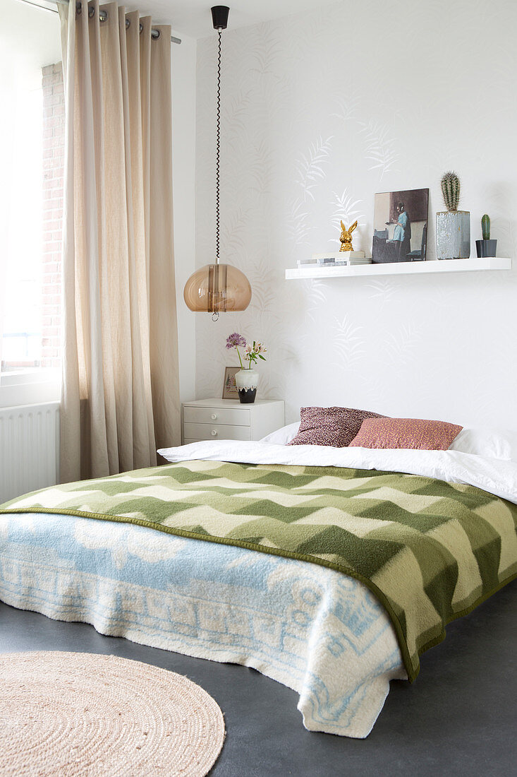 Doppelbett mit grün karierter Tagesdecke im Schlafzimmer