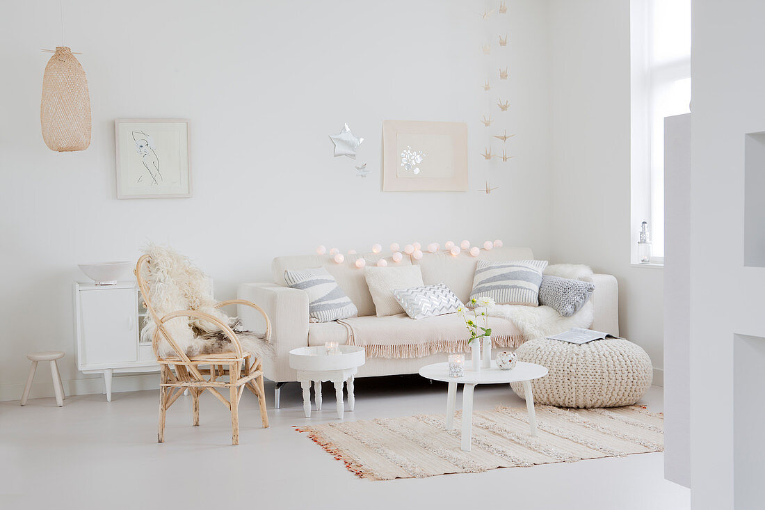 Couch mit Kissen, Tischchen, Sitzsack und Stuhl mit Fell in weihnachtlich dekoriertem, weißem Wohnzimmer