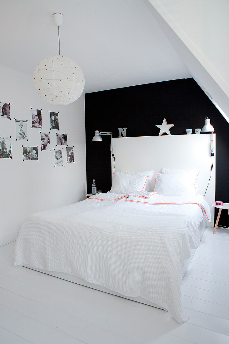 Weißes Doppelbett mit Betthaupt vor schwarzer Wand im Schlafzimmer