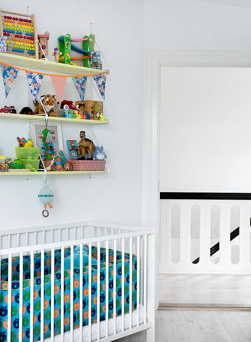 Shelves with toys above the crib in the white nursery