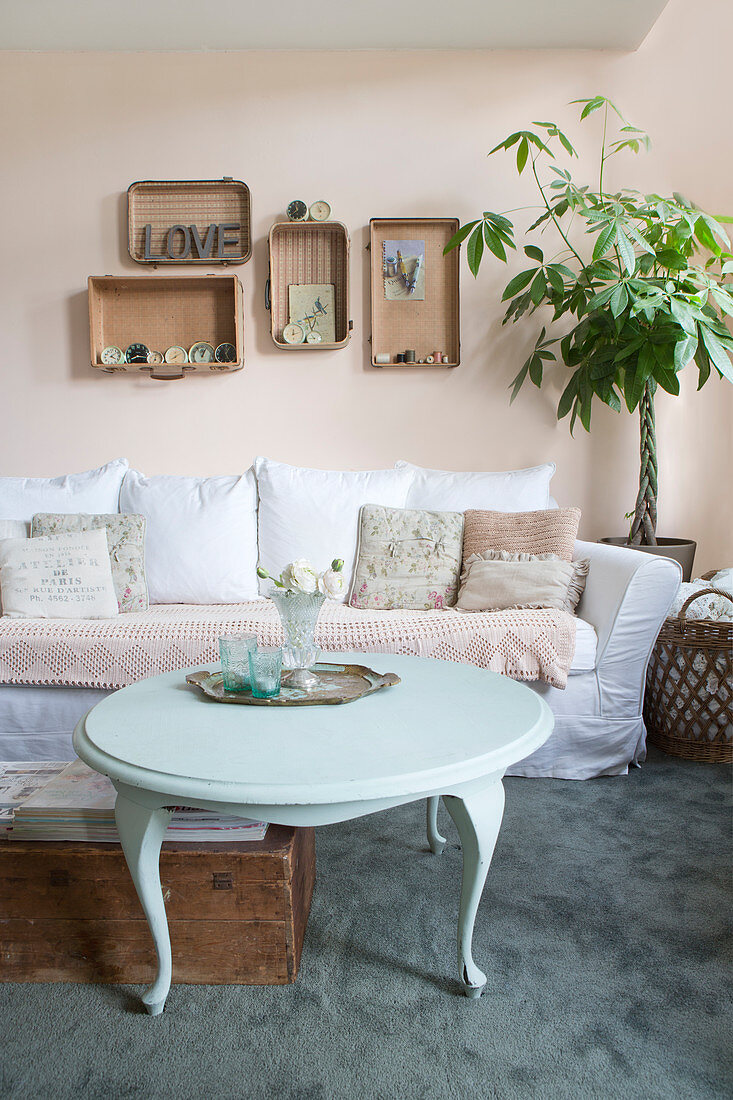 Runder Couchtisch vorm Sofa mit Spitzendecke im Wohnzimmer mit Vintage-Deko