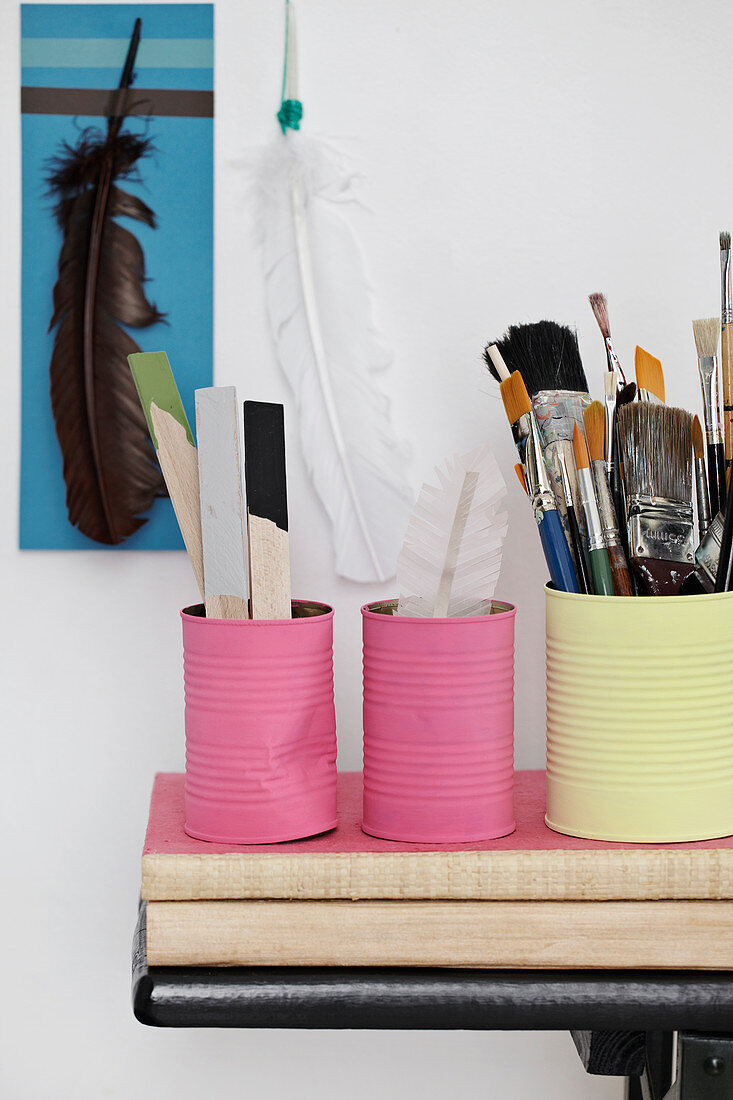 Painted tin cans in pink and yellow as a holder for brushes and crafting tools