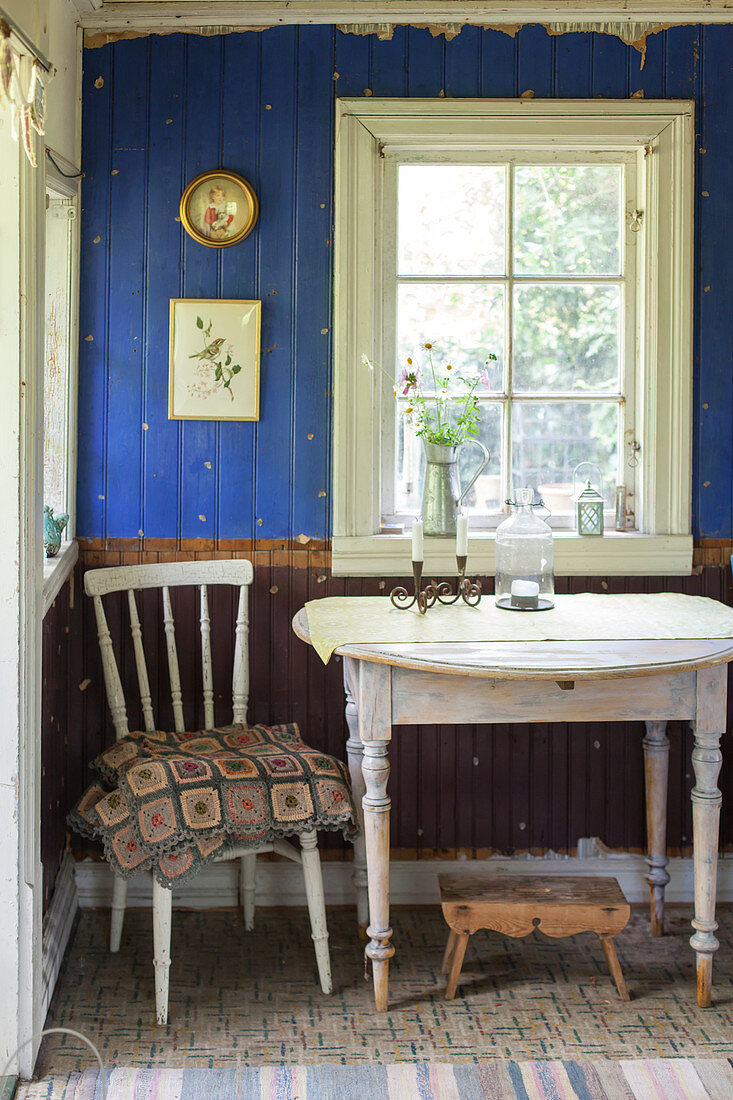 Alter Stuhl und Tisch vorm Fenster und zweifarbiger Bretterwand