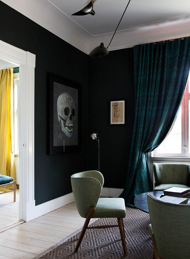 Retro-Sessel im Wohnzimmer mit schwarzer Wand und Totenkopf-Bild