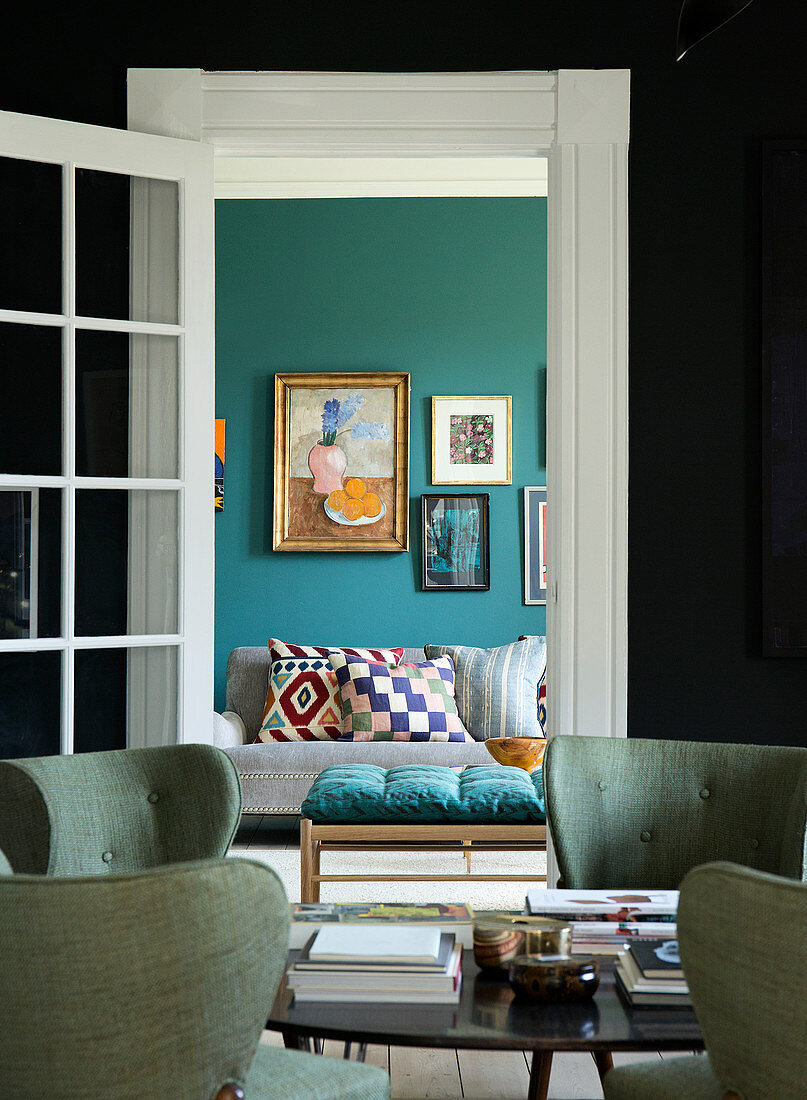 Polsterstühle im Retro-Stil, Blick ins Wohnzimmer mit petrolblauer Wand
