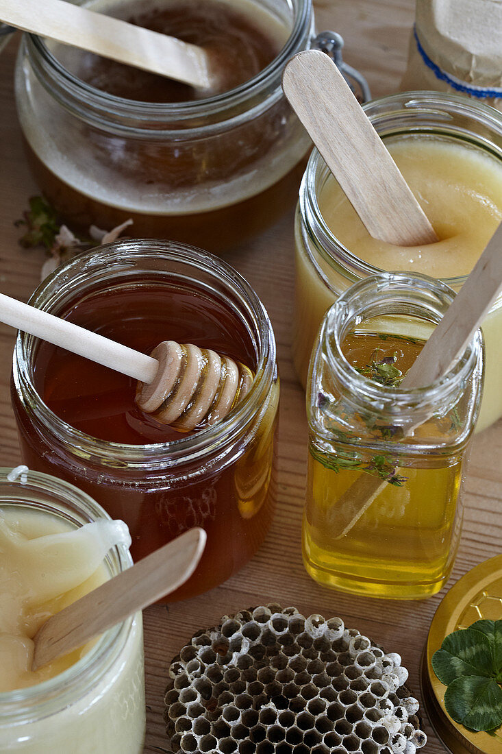 Verschiedene Honigsorten in Gläsern mit Holzspateln und Honiglöffel