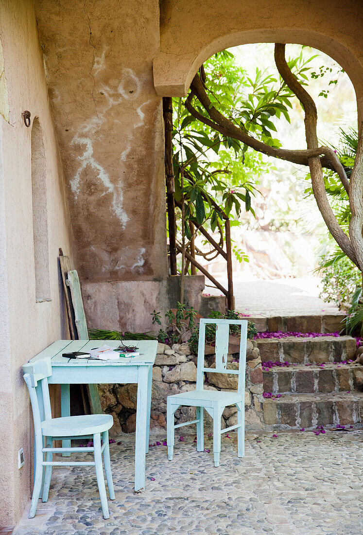 Hellblauer Holztisch und Stühle in mediterranem Innenhof