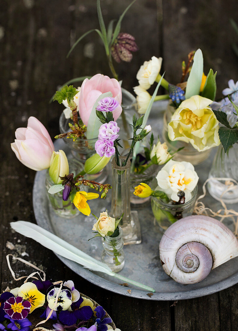 Spring flowers in different glass vases on a tray