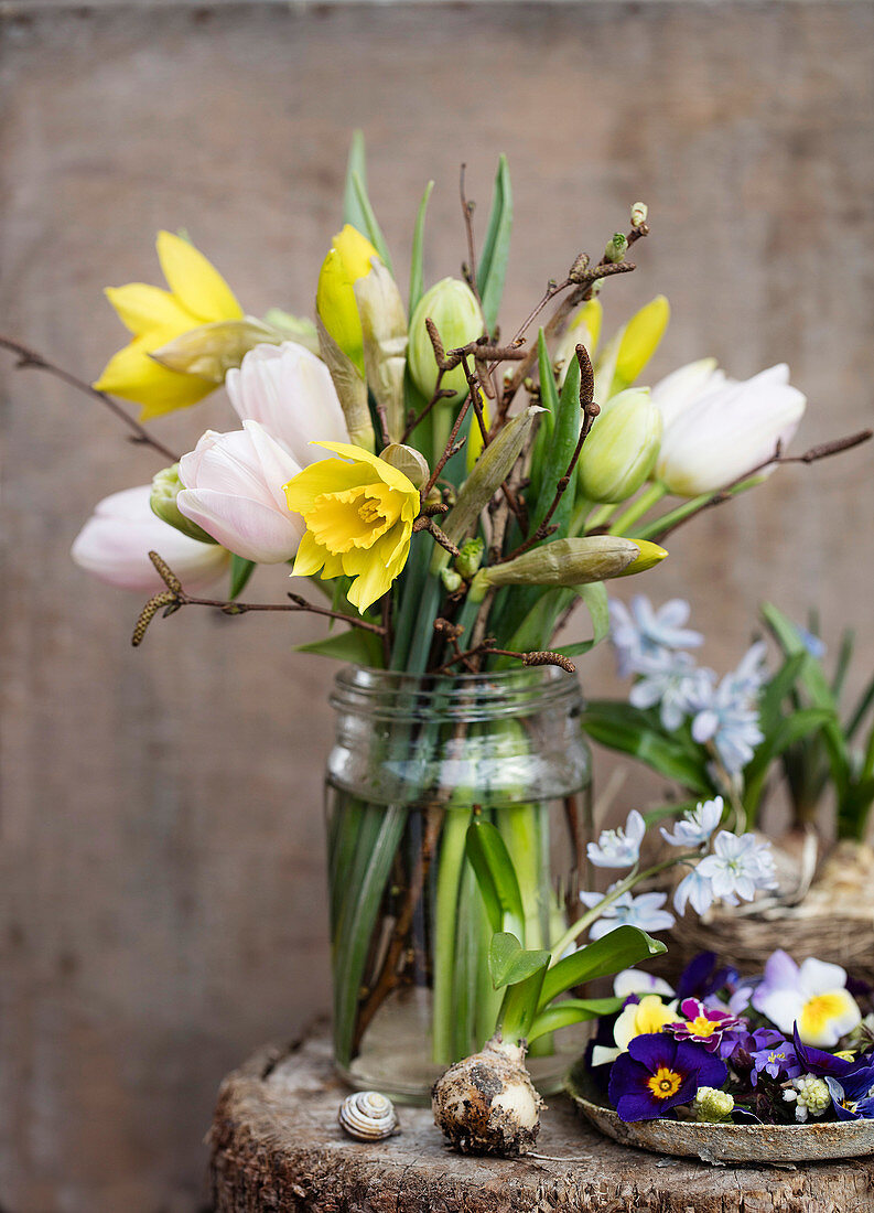 Osterstrauß mit Tulpen, Narzissen und Haselzweigen im Schraubglas