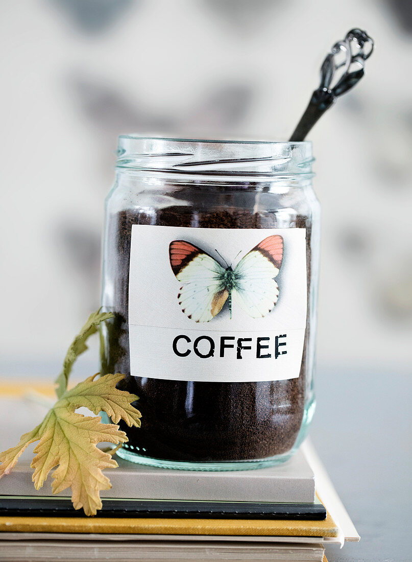Mit Schmetterling-Motiv beklebtes Schraubglas mit Kaffee