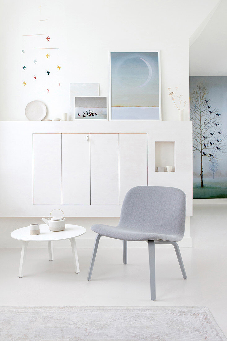 Gray upholstered chair and side table in front of a built-in cupboard