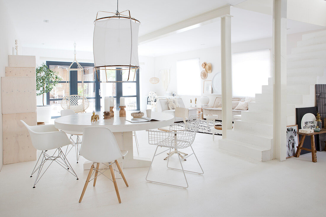 Runder Tisch mit Klassikerstühlen in weißem, offenem Wohnraum