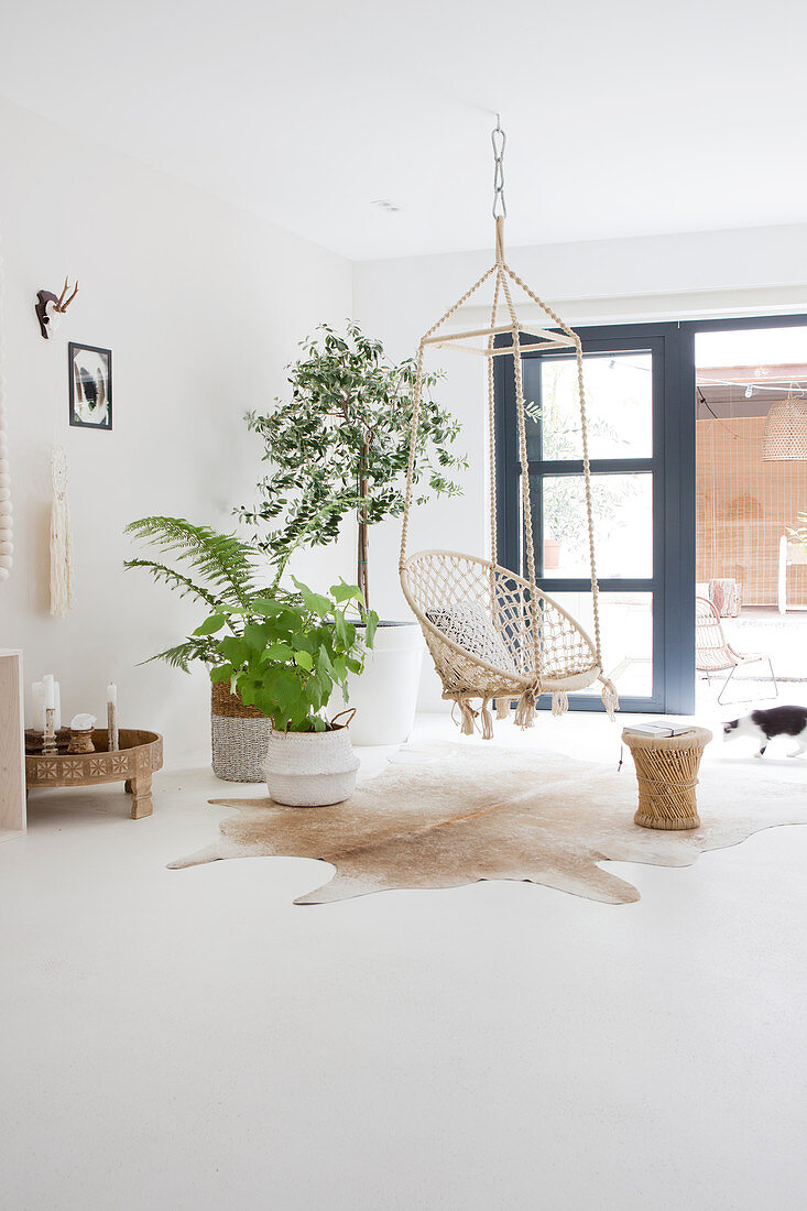 Hanging chair and houseplants in front of the patio door in a white living room