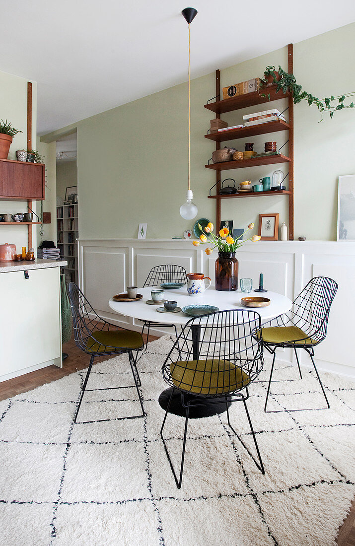 Wire chairs around a dining table on a rug in open-plan kitchen