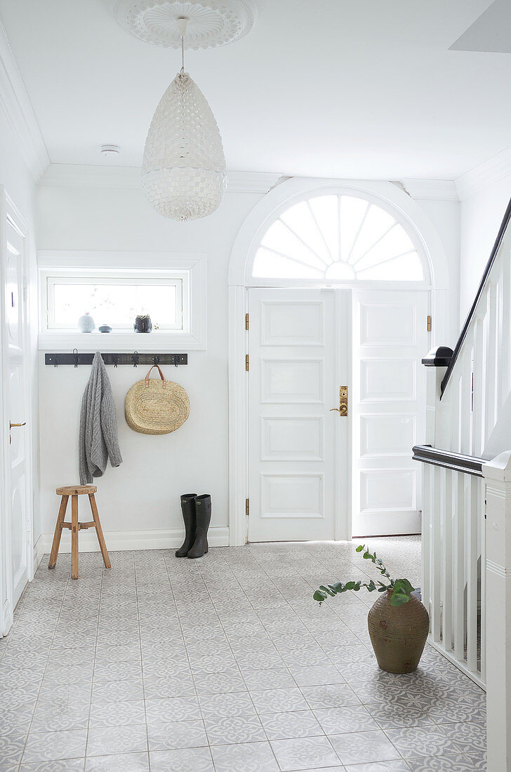 Wooden stool, coat rack, and boots in the hallway with staircase