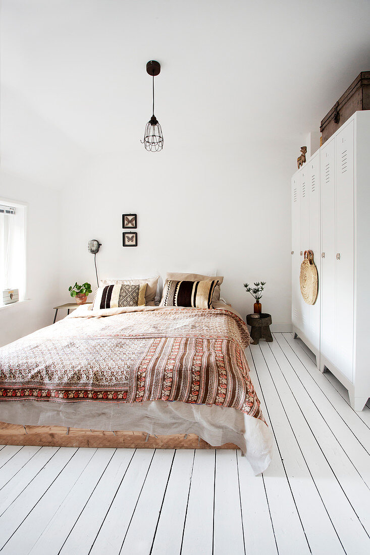 Schlafzimmer im Bohostil mit Spind als Kleiderschrank und Dielenboden