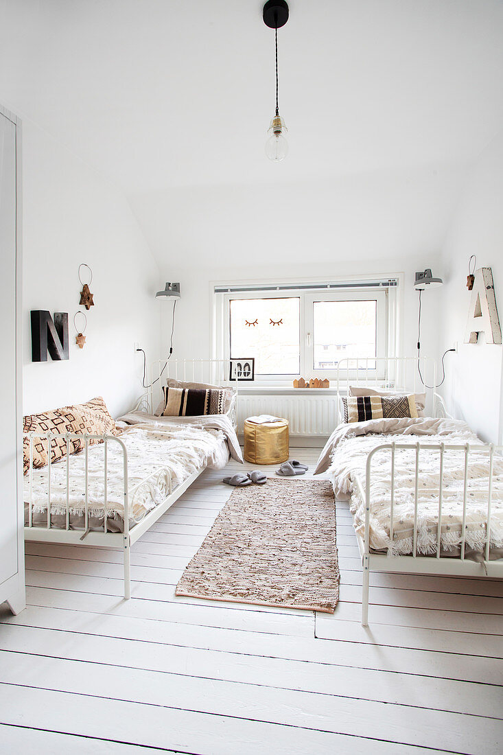 Schlafzimmer in Weiß mit zwei Metallbetten und Dielenboden