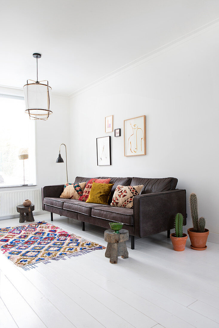 A colourful rug in front of a grey sofa with ethnic cushions and pictures on the wall