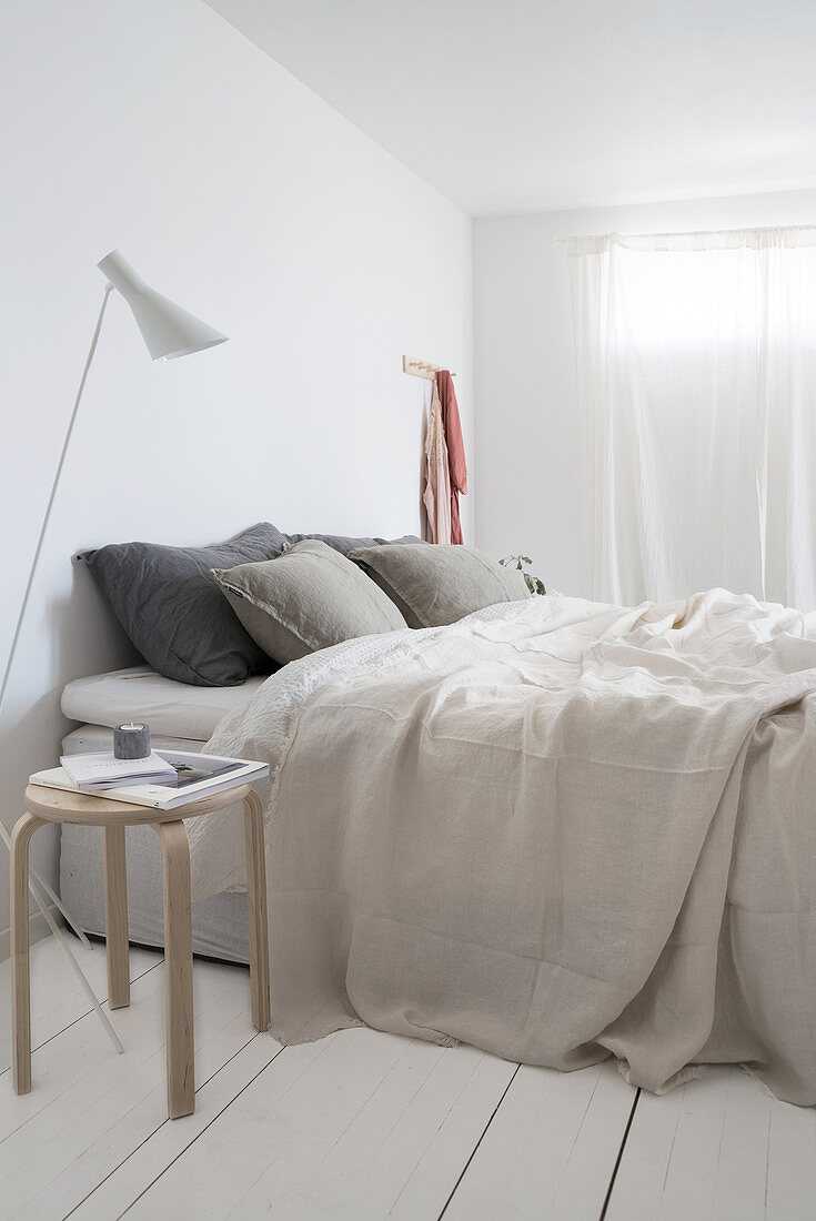 Doppelbett in minimalistischem Schlafzimmer mit weißer Dielenboden