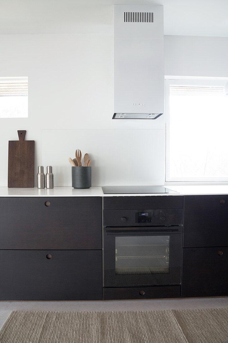 A dark kitchen unit with an extractor fan next to window