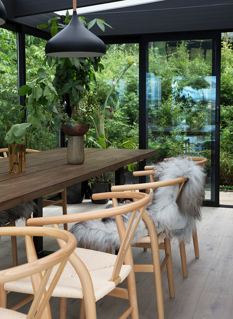A homemade wooden dining table with classic chairs in a conservatory