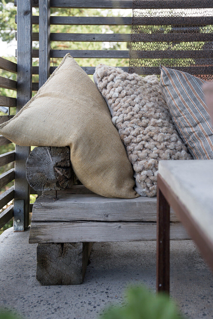 A rustic wooden bench with cushions on a terrace