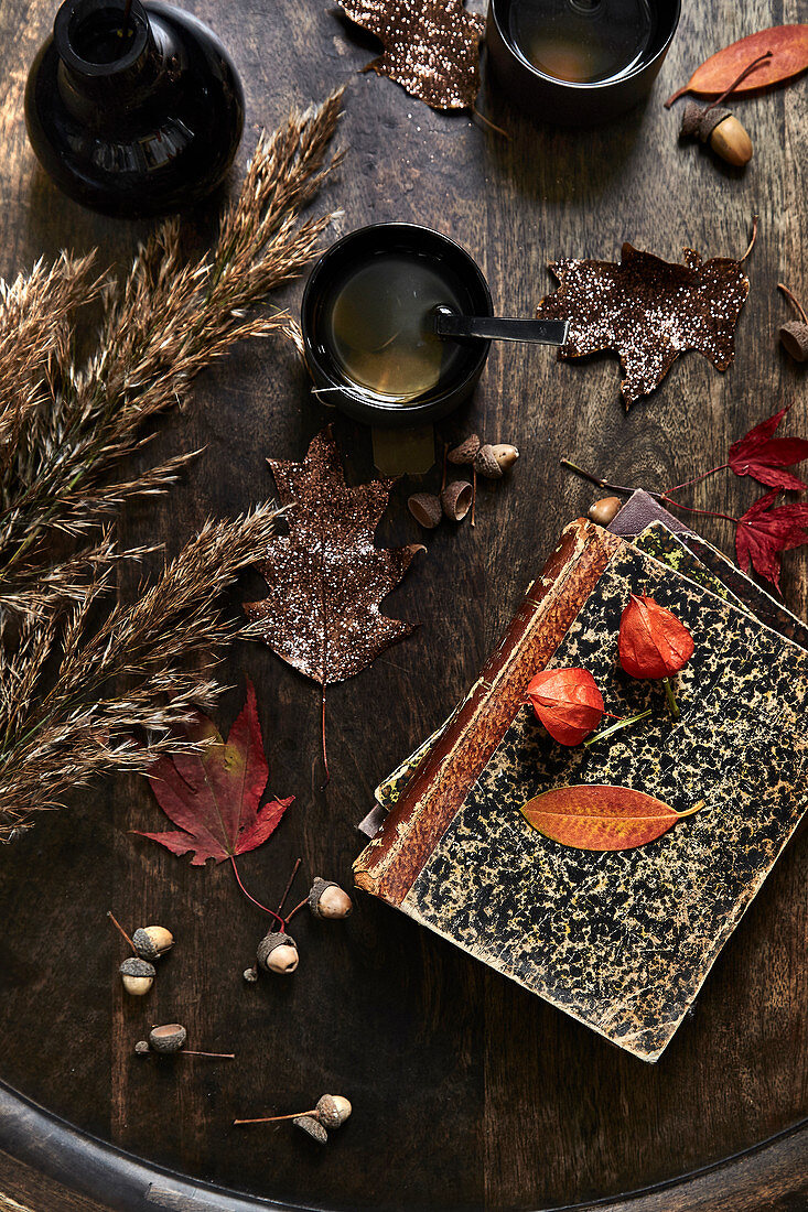 Old books, tea and autumnal decorations on a wooden table
