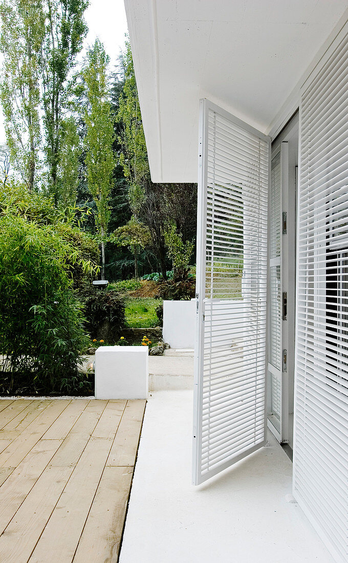 Open glass door with blinds leading to the terrace and the garden