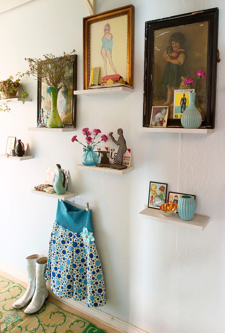 Bilder, Vasen und Krimskrams auf kleinen Regalbrettern an der Wand