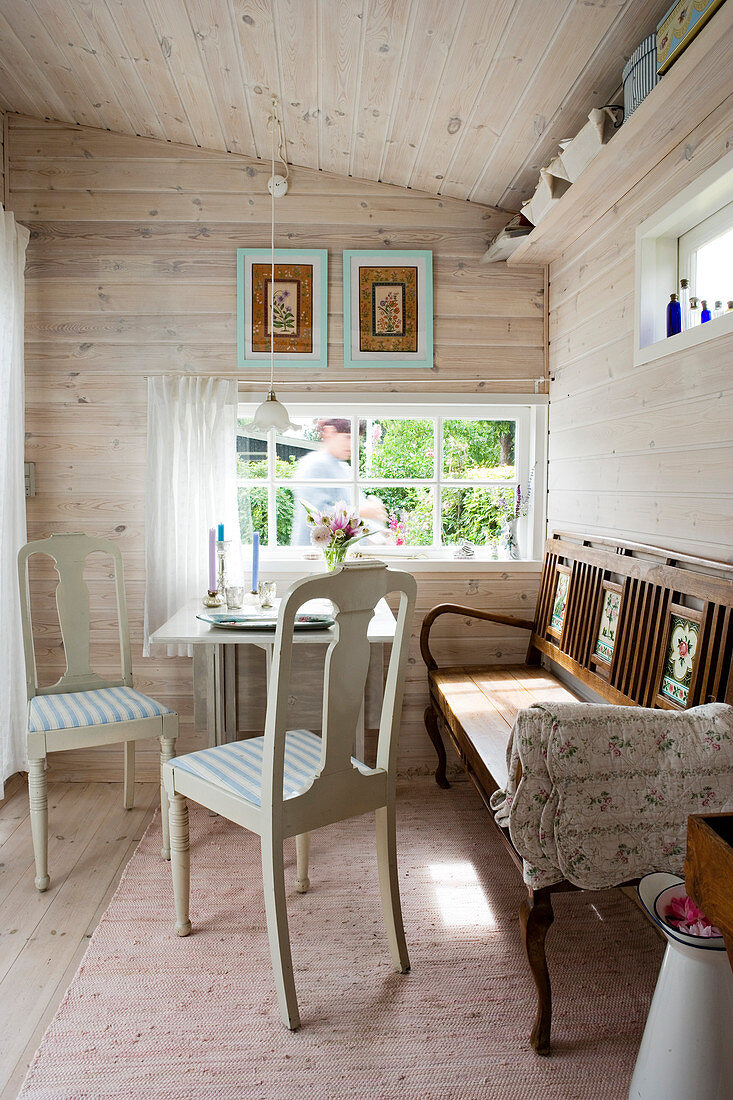 Antique chairs and an old bench at a table in a dining room with wall panelling