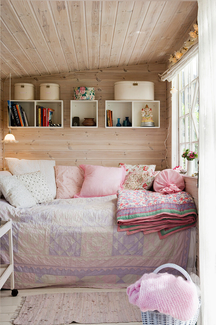 Gemütliches Tagesbett im kleinen Raum mit verkleideter Wand und Decke