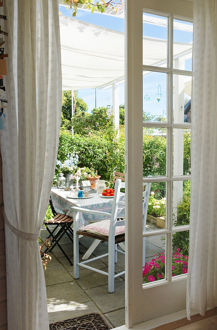 Blick durch offene Sprossentür auf den gedeckten Tisch auf der Terrasse