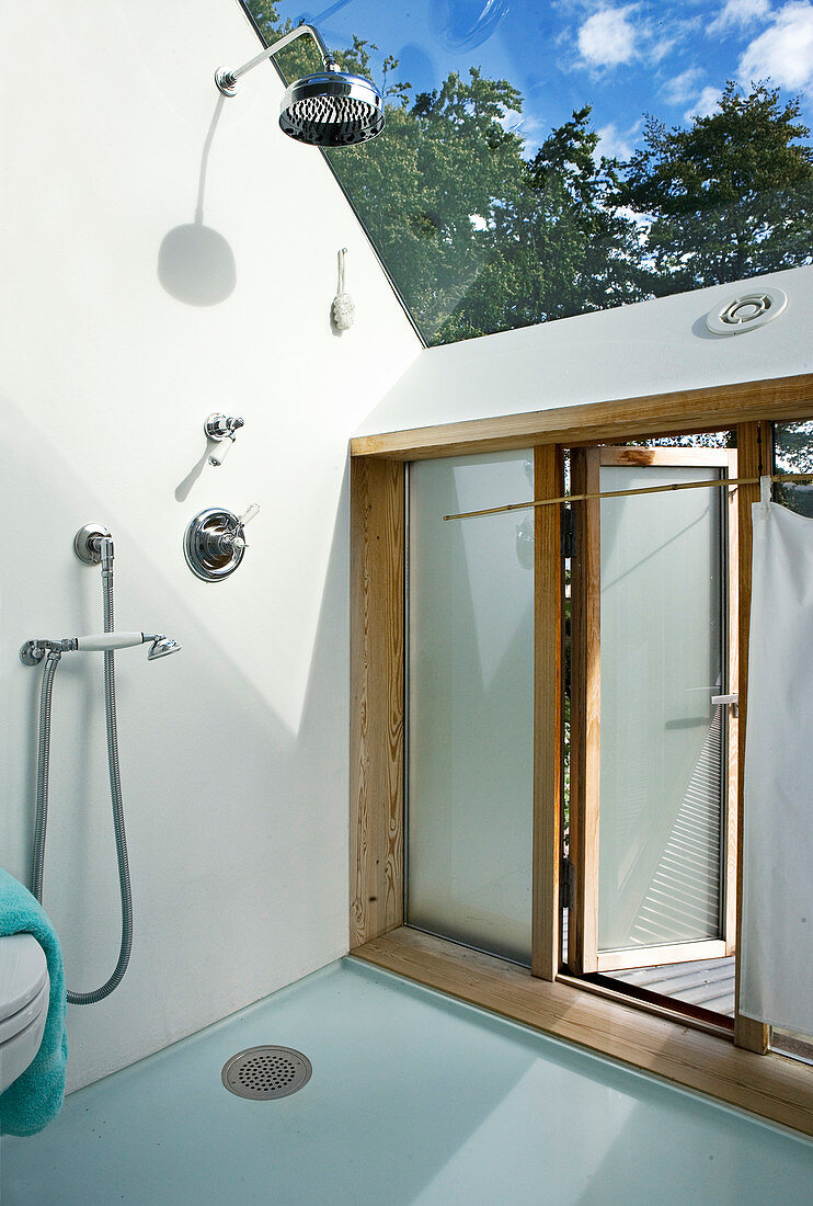 A shower in a bathroom with a glass roof and access to the garden