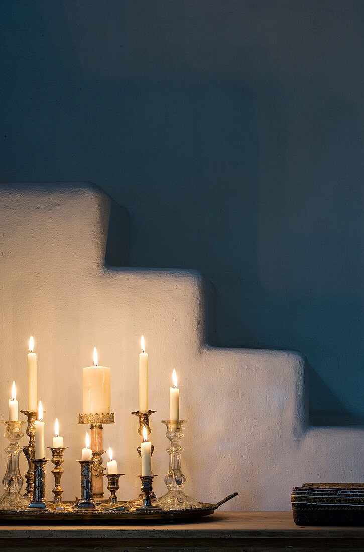 Group of candlesticks with burning white candles in front of plaster steps