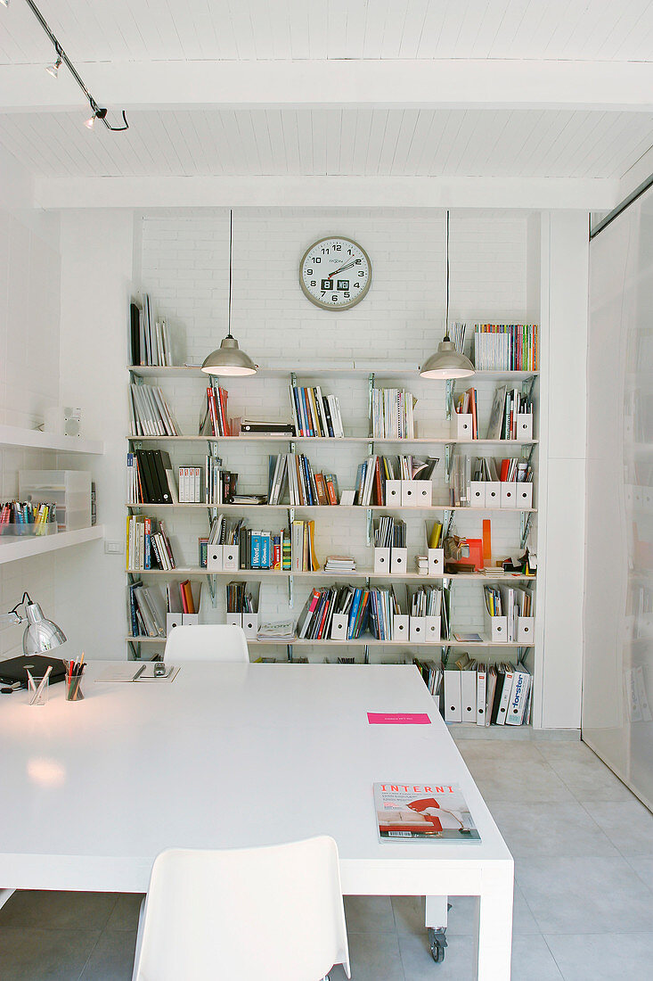 A large white table in an office with a bookshelf
