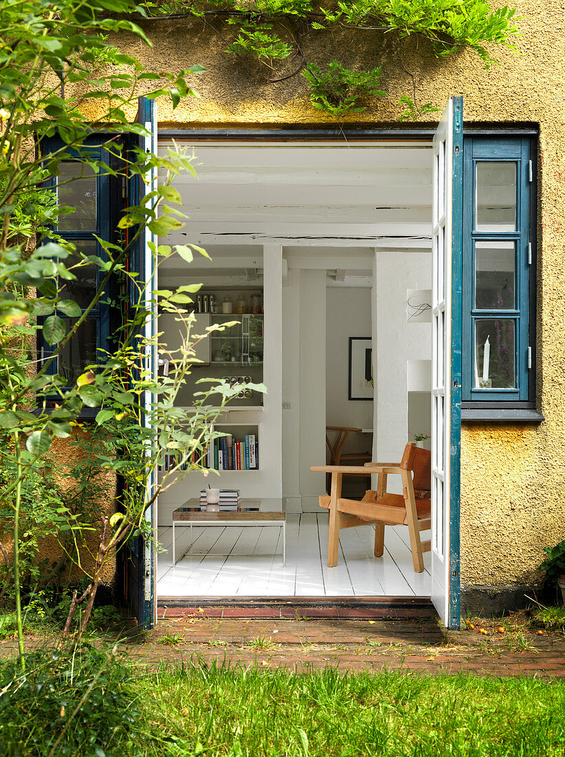 A view through open double doors from a garden into a living room