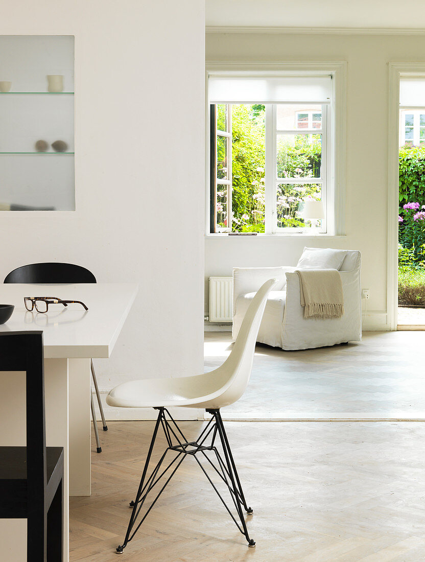 Designerstuhl am Esstisch vorm Durchgang zum Wohnzimmer mit Gartenzugang