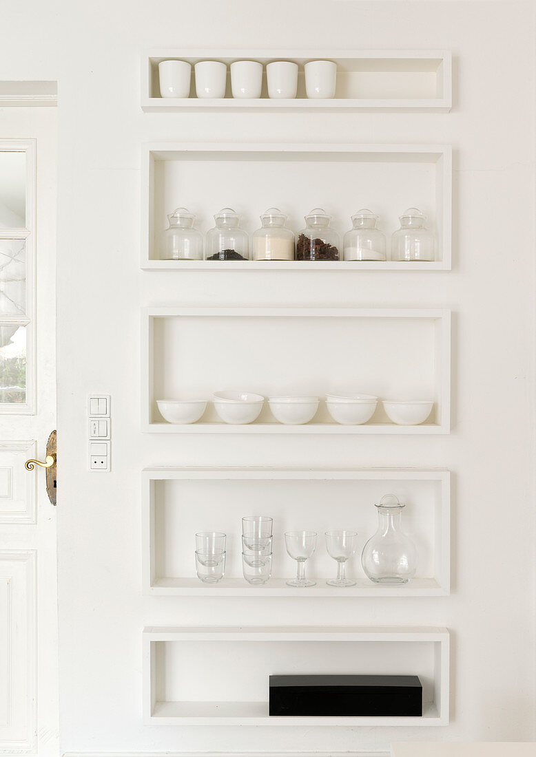 Regalkästen in weißer Wand mit Geschirr und Vorräten