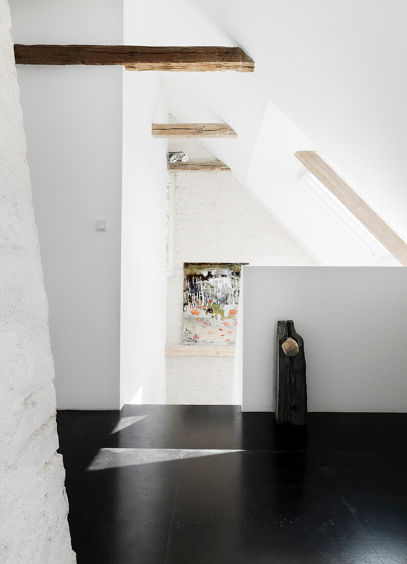 Black floor to the staircase with a sloping roof and wooden beams